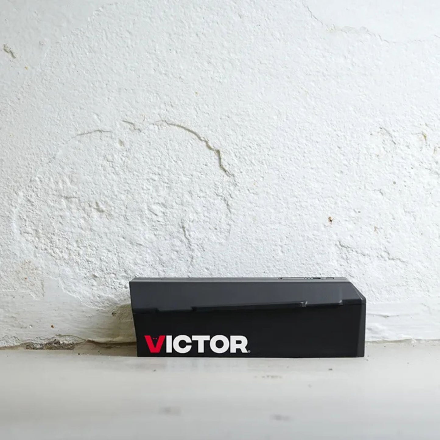 Black Victor mouse trap on a white surface with a white wall background